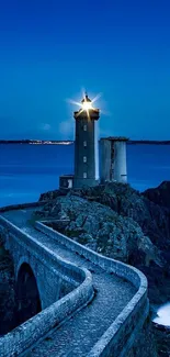 Lighthouse illuminating the dark blue night over the ocean.