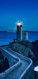 Nighttime lighthouse with ocean waves under a deep blue sky.