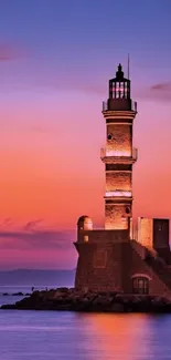 Lighthouse with vibrant sunset sky and calm ocean.