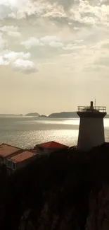 Lighthouse by the ocean under a cloudy sunset sky, serene coastal view.