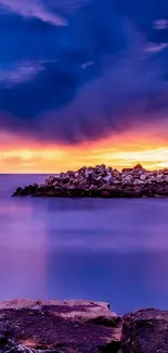 Lighthouse and rocks under a radiant sunset sky.