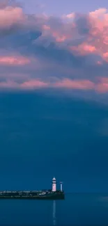 Lighthouse at sunset with pink clouds over the ocean.