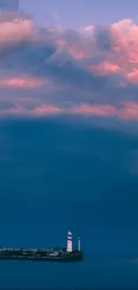 Lighthouse at dusk with pink clouds and calm ocean.