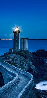 Tranquil lighthouse at night by the sea under a blue sky.