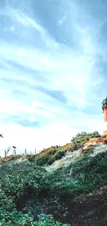 Lighthouse on a lush green hill under a clear blue sky.