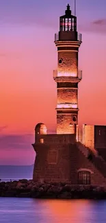 Lighthouse with a vibrant sunset backdrop over the sea.