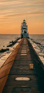 Lighthouse at the end of a pier during a warm, glowing sunset over the ocean.