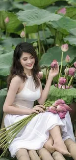 Woman sitting by lotus pond holding flowers, wearing white dress.