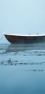 Solitary boat on a misty blue lake at dawn.