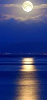 Full moon over calm ocean with serene blue sky.