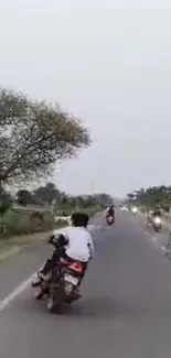 Motorcyclist rides along a peaceful country road under a serene sky.