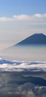 Mountain silhouette above clouds with serene sky.