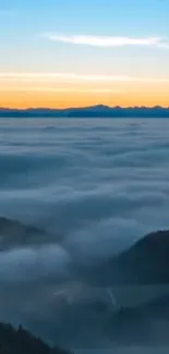 Mountains under a vibrant sunrise sky with clouds covering the valleys.