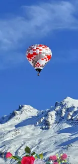 A hot air balloon over snowy mountains under a bright blue sky.