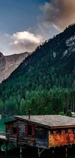 Serene mountain lake with forest and wooden cabin.