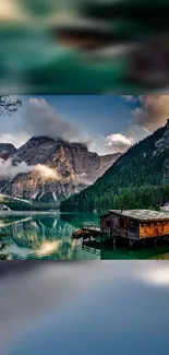 Serene lake with mountains and a cabin reflecting in calm waters.