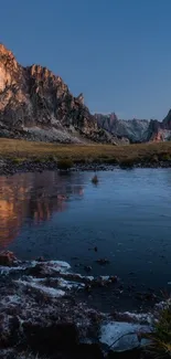 Serene mountain landscape with lake at sunset reflecting vibrant evening sky.