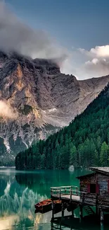 Serene lake with mountains and cabin in the background.