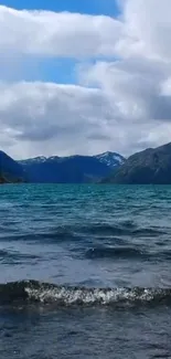 Serene mountain lake with blue water and cloudy sky background.