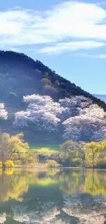 Serene mountain lake with reflections of spring blossoms under a clear sky.