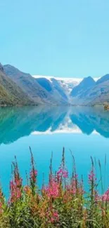 Serene mountain lake with blue sky and wildflowers, ideal for mobile wallpaper.