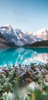 Turquoise mountain lake with snowy peaks under a clear blue sky.