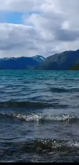 Serene lake with mountains under cloudy sky.