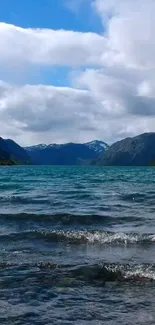 Serene mountain lake with blue water and green hills under a cloudy sky.