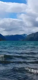 Serene mountain lake with blue water and cloudy sky background.