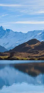 Snow-capped mountains reflecting in a clear blue lake under a serene sky.
