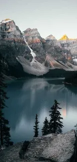 Serene mountain lake view at sunset with turquoise waters and rocky peaks.