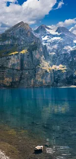 Serene mountain lake with clear blue water and towering rocky peaks under a blue sky.