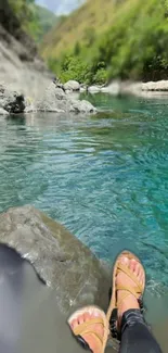 Feet dipped in a turquoise lake in a mountain setting.