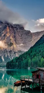 Serene mountain lake with cabin reflecting lush green forest.