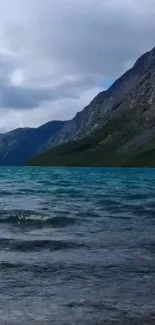 Serene mountain lake with cloudy sky and azure waters.