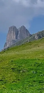 Serene mountain with green meadow under a blue sky.