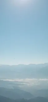 Serene mountain landscape with misty hills and a clear blue sky.