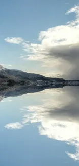 Serene mountain reflection on calm lake with blue sky and clouds.