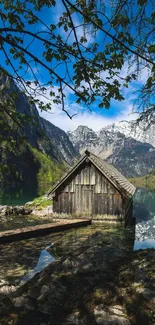 Rustic cabin by a lake with mountain background.