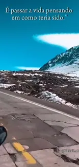 Scenic mountain road with snow-covered peaks under a bright blue sky.