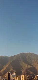 Mountain skyline with blue sky and city buildings at sunset.