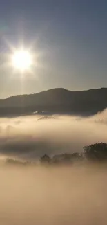 Misty mountain sunrise with sunlight shining over the fog in a calm landscape.