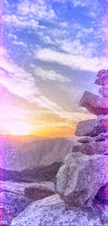 Stacked rocks with a sunrise over a mountain landscape.