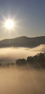 Serene sunrise over misty mountains with sun rays and a blue sky.