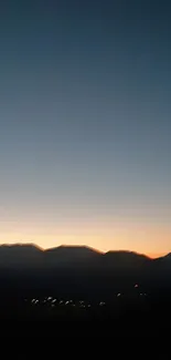 Serene mountain silhouette at sunset against dusk sky.