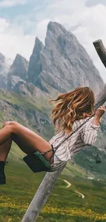 Woman on swing with mountain backdrop.