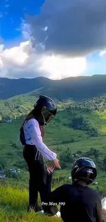 Breathtaking mountain view with two people in helmets overlooking lush landscape.