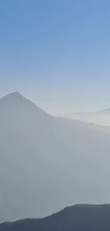 Misty mountains against a serene blue sky.