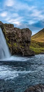 Mountain waterfall with clear blue sky and tranquil scenery.