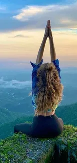 Woman practicing yoga on mountain edge at sunset with scenic view.